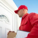 Kurir berseragam merah memegang paket di depan pintu rumah saat proses pengiriman barang